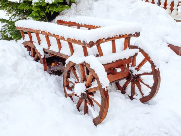 Trä röd dekorativ vagn står i en snödriva täckt med snö — Stockfoto