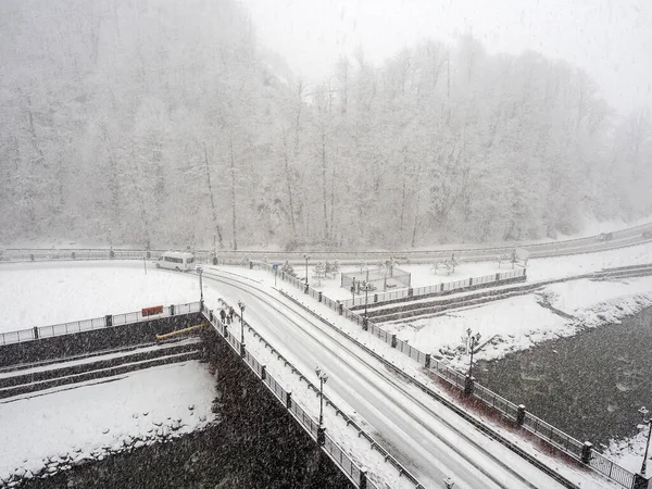 Kilátás a folyó feletti hídra hóesésben, havas járdákkal és csupasz fákkal — Stock Fotó