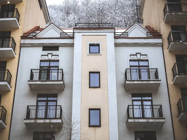 Casa con ventanas en el centro y balcones en los lados y bosque en la parte superior en el fondo — Foto de Stock