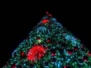 Gökyüzüne karşı karanlıkta parlayan bir sürü ışık ve noel balosu olan büyük noel ağacı.