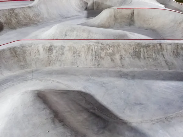 Concrete skate park with bowls and ramps. Full screen photo