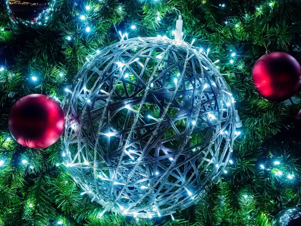 Una grande palla di Natale di ghirlande pende tra i rami e le palle di abete — Foto Stock