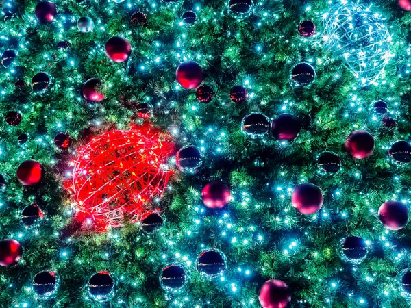さまざまなボールとガーランドを持つクリスマスツリーの枝は、暗闇の中で照らされています。背景色 — ストック写真