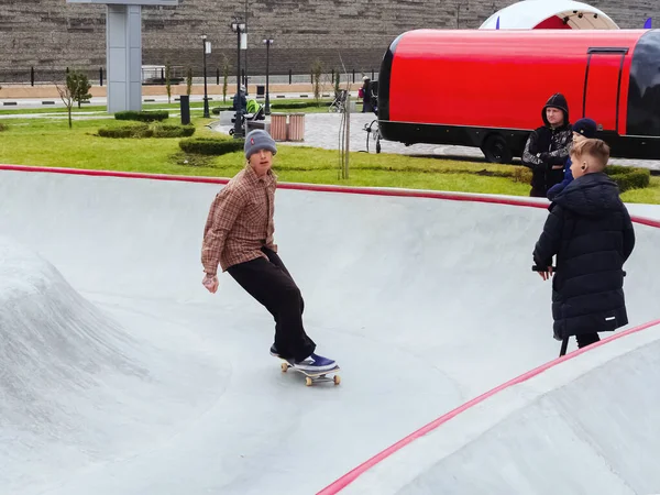 Sotsji, Rusland - 26 december 2019. Een man rijdt op een skateboard in een skatepark en andere jongens houden hem in de gaten in de buurt — Stockfoto