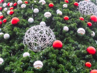 Bir sürü kırmızı ve gümüş topları olan yeşil ladin dalları ve birbirine sarılmış iki büyük hasır top.