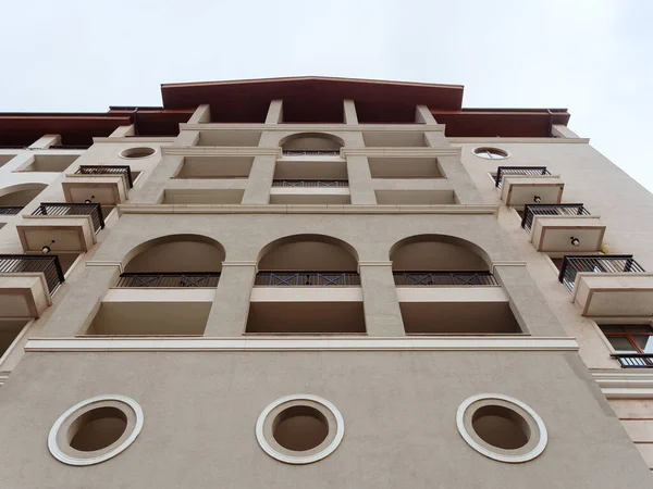 Vista inferior de un edificio gris con balcones arqueados alrededor de agujeros decorativos y un techo rojo — Foto de Stock