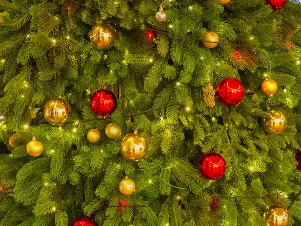 Kalın Noel ağacı süslenmiş kırmızı ve altın toplarla süslenmiş çelenk ile aydınlatılmış — Stok fotoğraf