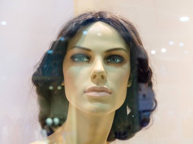 Cam vitrininin arkasındaki gerçekçi kadın mankenin başı.