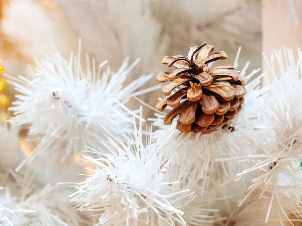 Beyaz bir Noel ağacının yapay dalları arasında gerçek bir kozalak. — Stok fotoğraf