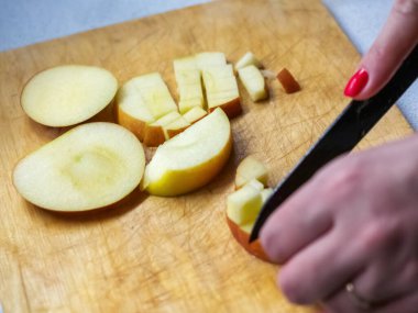 Kesme tahtasında elmayı küçük parçalara bölme odaklı bir fotoğraf.
