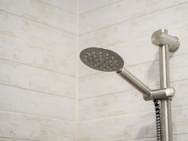 Серебряный глазированный душ висит на стене с черепицей, имитирующей дерево — стоковое фото
