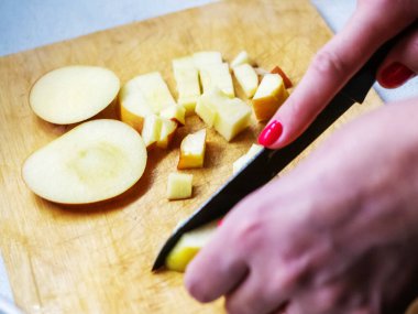 Merkezde odaklanmış bir fotoğraf kesme tahtasındaki elmayı küçük parçalara ayırıyor.