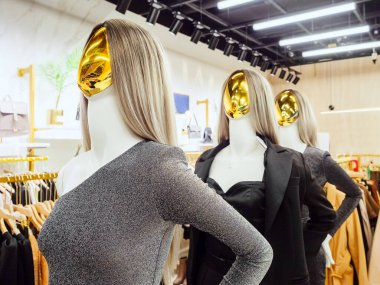 Akşamları altın yüzlü soyut mankenler butikte duruyor.
