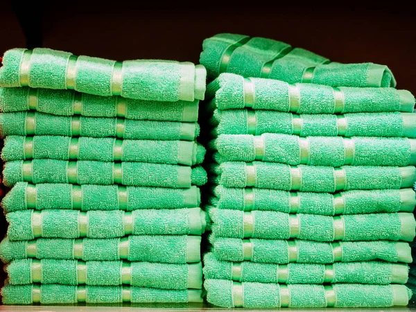 Toalhas terry idênticas verdes claras empilhadas em pilhas na loja — Fotografia de Stock