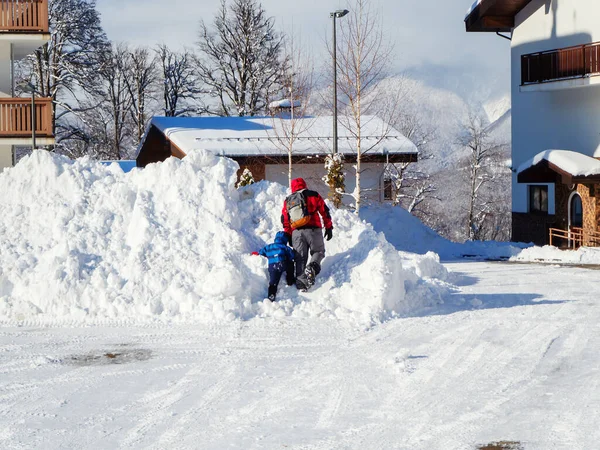 En man och ett barn går in i en gigantisk snödriva en solig vinterdag — Stockfoto