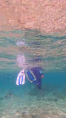 Mavi paletlerle su altında şnorkelle yüzen biri.