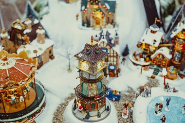Oyuncak Noel Seramik Minyatür karla kaplı şehir ve insanlar yürüyen modeli ile. Saat Kulesi ile küçük bir festival köy. Retro filtre efekti. Seçici odak, kopya alanı