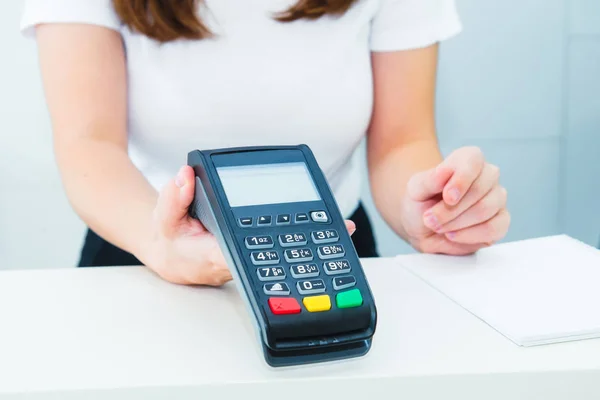 Seller holds payment terminal in hands. Contactless payment with nfc technology at shop, clinic, hotel. Mobile payment PayPass. Selective Focus on hands. Copy space