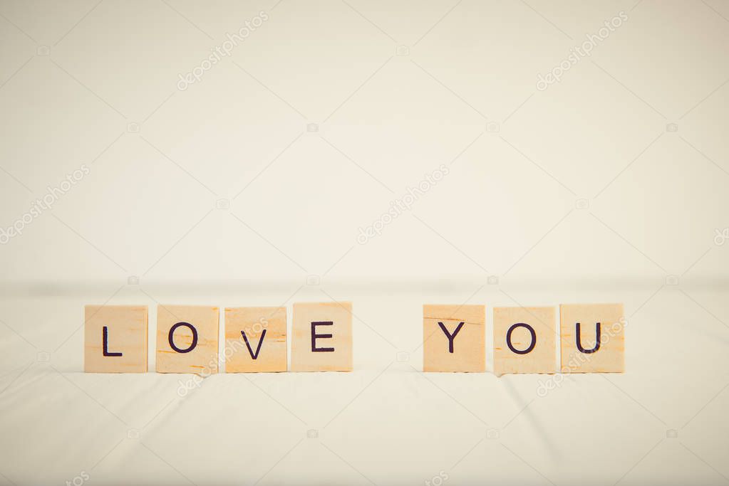 Message I love you spelled in wooden blocks standing on white wooden table. Valentines day background. Simplicity concept. Vintage tonning. Copy space