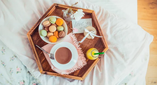Breakfast in bed with i love you text on a note. Cup of coffee, juice, macaroons, rose and giftbox on wooden tray. Romantic breakfast in bed. Birthday, Valentine\'s day morning. Wide banner. Copy space.