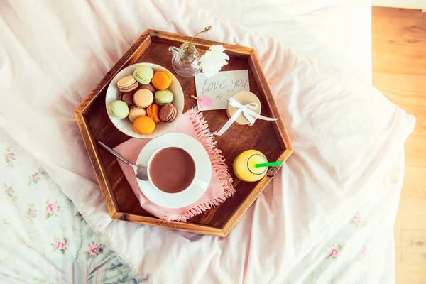 Breakfast in bed with i love you text on a note. Cup of coffee, juice, macaroons, rose flower and giftbox on wooden tray. Romantic breakfast in bed. Birthday, Valentine's day morning. Copy space — Stock Image Breakfast Bed Love You Text Note Cup Coffee Juice Macaroons Stock Image