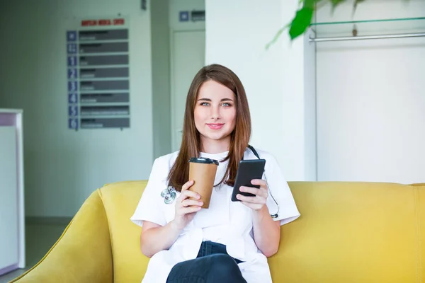 Young Female Doctor Sitting Yellow Sofa Medical Centre Mobile Phone — Stock Photo, Image