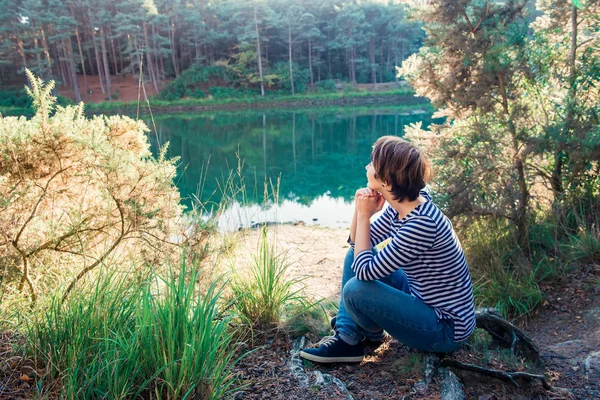사이드 보기의 꿈꾸는 여자는 호숫가에 앉아서 고요한 호수와 즐기는 목가적인 — 스톡 사진
