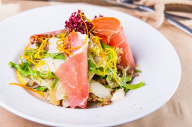 Yeşil salatası jambon ile kapatın ve armut beyaz tabak içinde yakın çekim. Servis restoran tablo. Seçici odak, kopya alanı