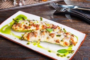 Kabak dolması tekneler pişmiş. Koyu ahşap masa üzerinde beyaz tabakta servis et ve peynir ve pesto soslu kabak dolması. Sağlıklı gıda kavramı