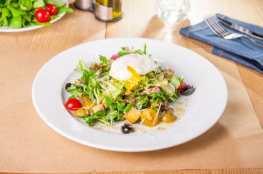 Yeşil sebze salatası ton balığı ve haşlanmış yumurta ahşap servis masada beyaz tabakta. Seçici odak, kopya alanı