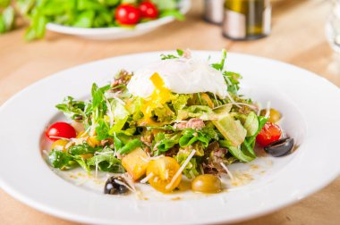 Yeşil sebze salatası ahşap servis masada beyaz tabakta ton balığı ve haşlanmış yumurta ile kapatın. Seçici odak, kopya alanı