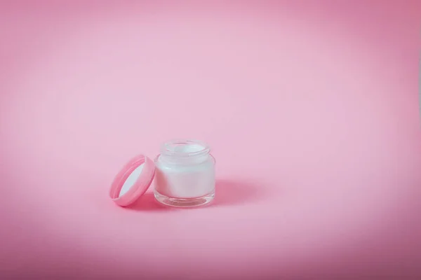 Tarro abierto con crema facial o corporal sobre fondo rosa aislado. Belleza, maquillaje, concepto de cuidado de la piel. Enfoque selectivo, espacio de copia . —  Fotos de Stock