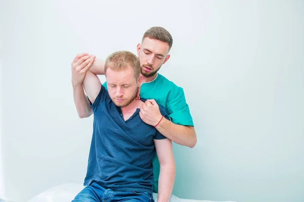Manlig patient som får massage från terapeut. En kiropraktor stretching hans patientens ryggrad och händer i medicinskt kontor. Neurologisk undersökning. Osteopati, kiropraktik, fysioterapi. — Stockfoto