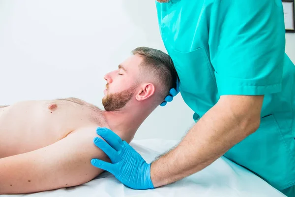 Paciente do sexo masculino recebendo massagem do terapeuta. Um quiroprático a esticar o pescoço do paciente no consultório médico. Exame físico neurológico. Osteopatia, quiropraxia, fisioterapia. Isolados . — Fotografia de Stock