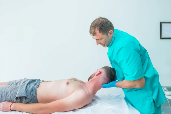 Paciente do sexo masculino recebendo massagem do terapeuta. Um quiroprático a esticar o pescoço do paciente no consultório médico. Exame físico neurológico. Osteopatia, quiropraxia, fisioterapia. Isolados . — Fotografia de Stock