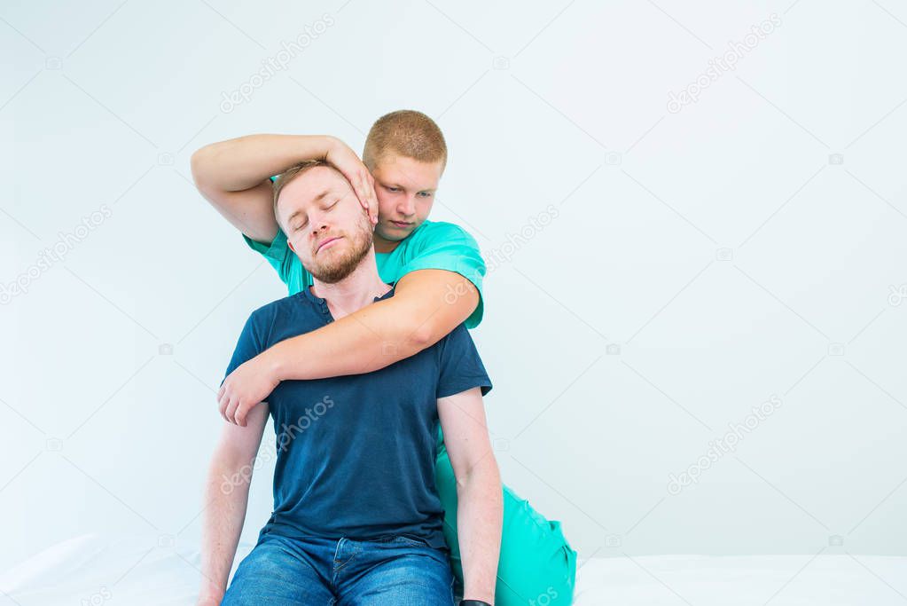 Male patient receiving massage from therapist. A chiropractor stretching his patient's neck in medical office. Neurological physical examination. Osteopathy, chiropractic, physiotherapy. Isolated.