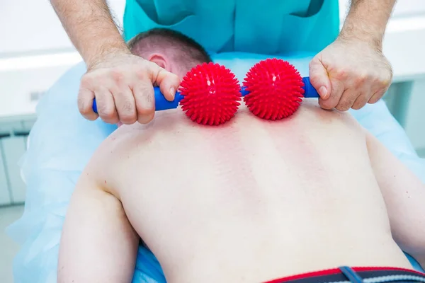 Jovem na fisioterapia recebendo massagem de bola do terapeuta. Um quiroprático trata a coluna torácica do paciente em consultório médico. Neurologia, osteopatia, quiropraxia. Foco seletivo, Fechar — Fotografia de Stock