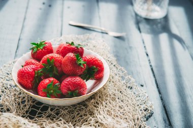 Kapatın Rustik siyah ahşap mutfak masası geri sabah ışığı ile aydınlatılmış seramik kase taze toplanan sulu organik çilek. Çiftçi hasadı, yerel pazar. Seçici odaklama, Boşluk kopyalama.