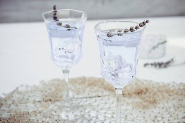 Beyaz ahşap masa üzerinde güzel bardak çiçekler ve buz küpleri ile Taze lavanta limonata kapatın. Detoks suyu. Yaz içkisi. Diyet kokteyli. Seçici odak. Kopyalama alanı.