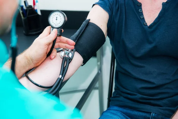 Közelről férfi orvos segítségével vérnyomásmérő sztetoszkóp ellenőrzése vérnyomás egy fiatal férfi beteg a kórházban. Egészségügy, egészséges életmód és orvosi szolgáltatás koncepció. Lemezterület másolása. — Stock Fotó