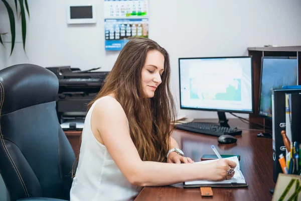 Young caucasian business lady sitting on her workplace in office. Female entrepreneurship. Portrait of skilled manager satisfied with occupation. Selective focus, copy space. — Stock Photo, Image