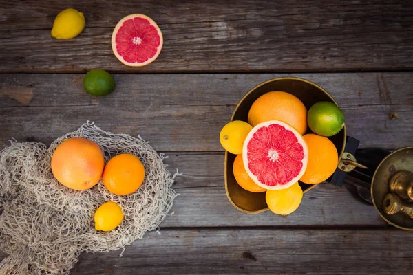 Topp Visa färska citrusfrukter i Vintage skala och flera apelsiner, citroner, grapefrukt, lime på den gamla rustika träbord med några vikter. Detox diet. Skörde konceptet. Bondemarknaden. Kopiera utrymme. — Stockfoto