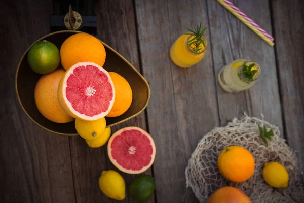 Topp Visa färska citrusfrukter i Vintage skala och flera apelsiner, citroner, grapefrukt, lime och lemonad flaskor på den gamla rustika träbord. Detox diet. Skörde konceptet. Sumer drycker. Kopiera utrymme. — Stockfoto