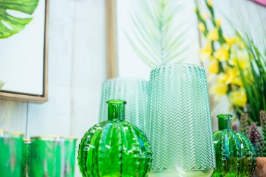 Açık yeşil cam vazoların yakın kompozisyonu, beyaz arka planda tropikal yaprak olan poster çerçevesi. Modern İskandinav tarzı hafif iç tasarım detayları. Yumuşak seçici odaklanma. Boşluğu kopyala