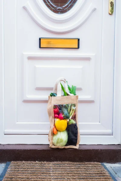 Fresh organic vegetable delivery concept. Reusable bio eco sackcloth fabric bag packagingstanding near entering house door. Local farmer healthy food. Zero-waste, plastic-free lifestyle. Copy space. — Stock Photo, Image