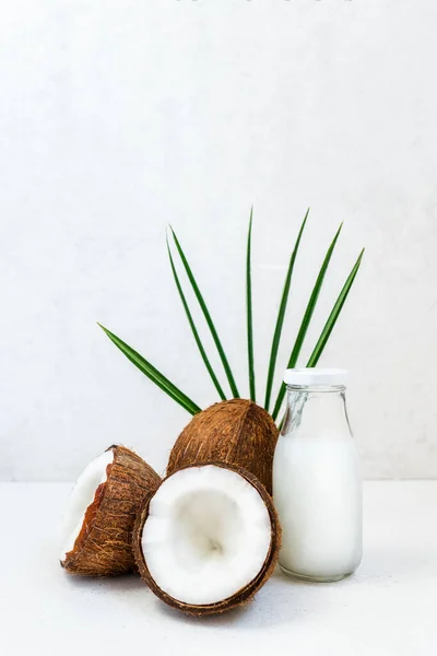Vers, gezond veganistisch basis kokosmelk met hele noten en pulm blad op de witte achtergrond. Natuurlijke kokosolie voor koken en huidverzorging. Selectieve focus. Verticale kaart. Kopieerruimte. — Stockfoto