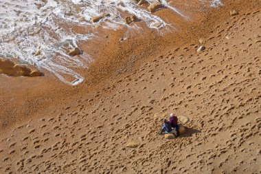 Üst düzey üst düzey çift dinleniyor ve denize bakıyor boş kumsaldaki kayanın üzerinde oturuyorlar. Sakinleşmek ve hayatın tadını çıkarmak. Duygusal sağIık. Mutluluk küçük şeylerdedir. Boşluğu kopyala.