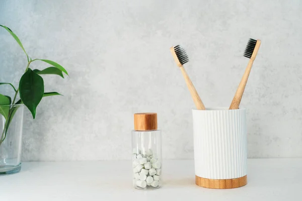 Artículos de baño de cero residuos. Cepillos de dientes de bambú en soporte de material de reciclaje, pestañas de enjuague bucal natural y plantas verdes frescas en vidrio. Esenciales de cuidado oral. Hogar respetuoso del medio ambiente. Minimalismo. Copiar espacio. — Foto de Stock