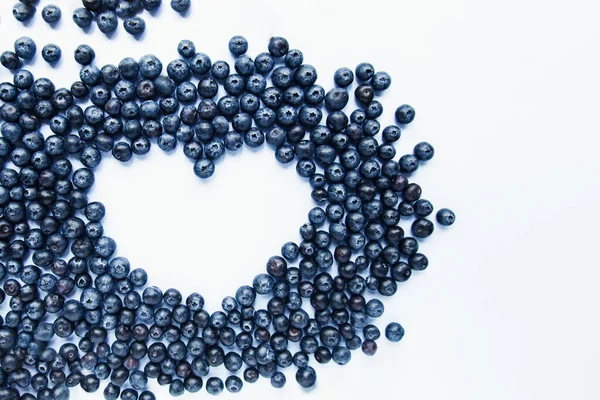 Forma de corazón de arándanos frescos sobre fondo blanco. Comida saludable, bayas de verano. Concepto de comida mínima. Flatlay. Enfoque selectivo. Copiar espacio. — Foto de Stock