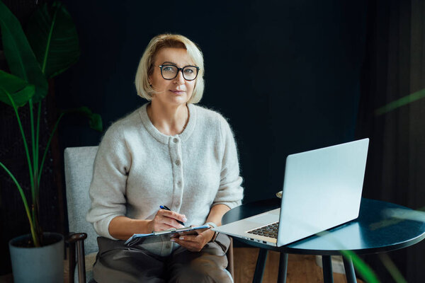 Professional Psychotherapy. Successful female Psychologist Smiling To Camera Sitting On armchair In Office. Mature 50s middle-age professional portrait of teacher, coach, mentor, therapist, counselor.